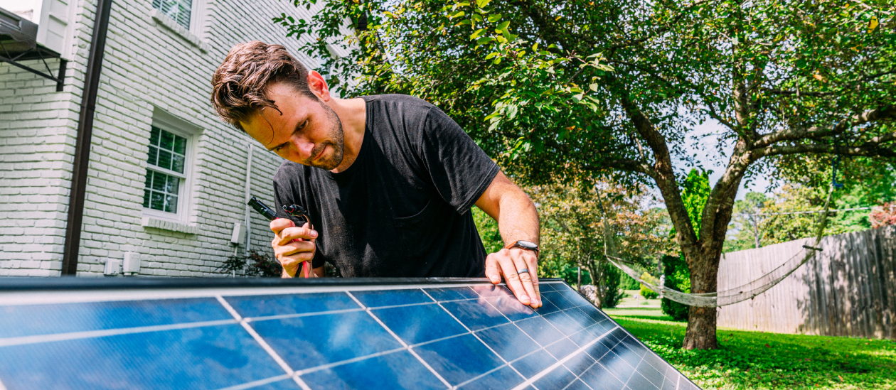 A homeowner considers DIY solar panels, inspecting a module outside his home